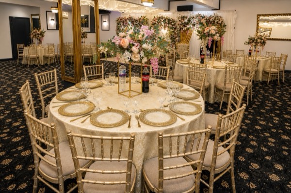 An elegantly dressed table with gold place settings and a floral centrepiece